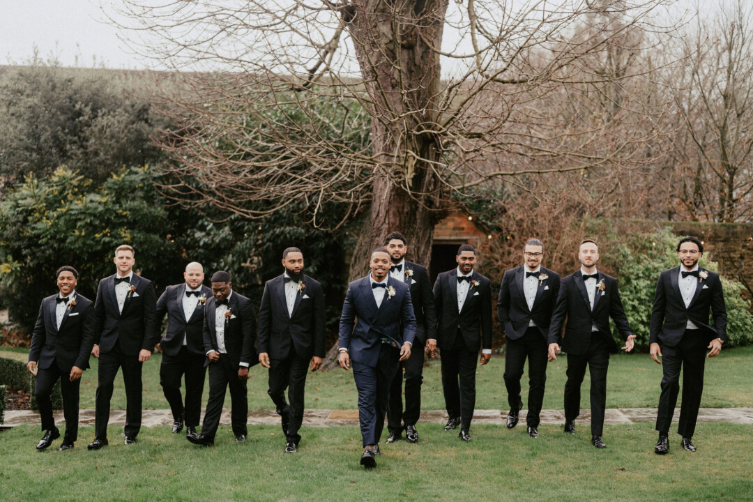 Groomsmen in black tie in the farmhouse garden.